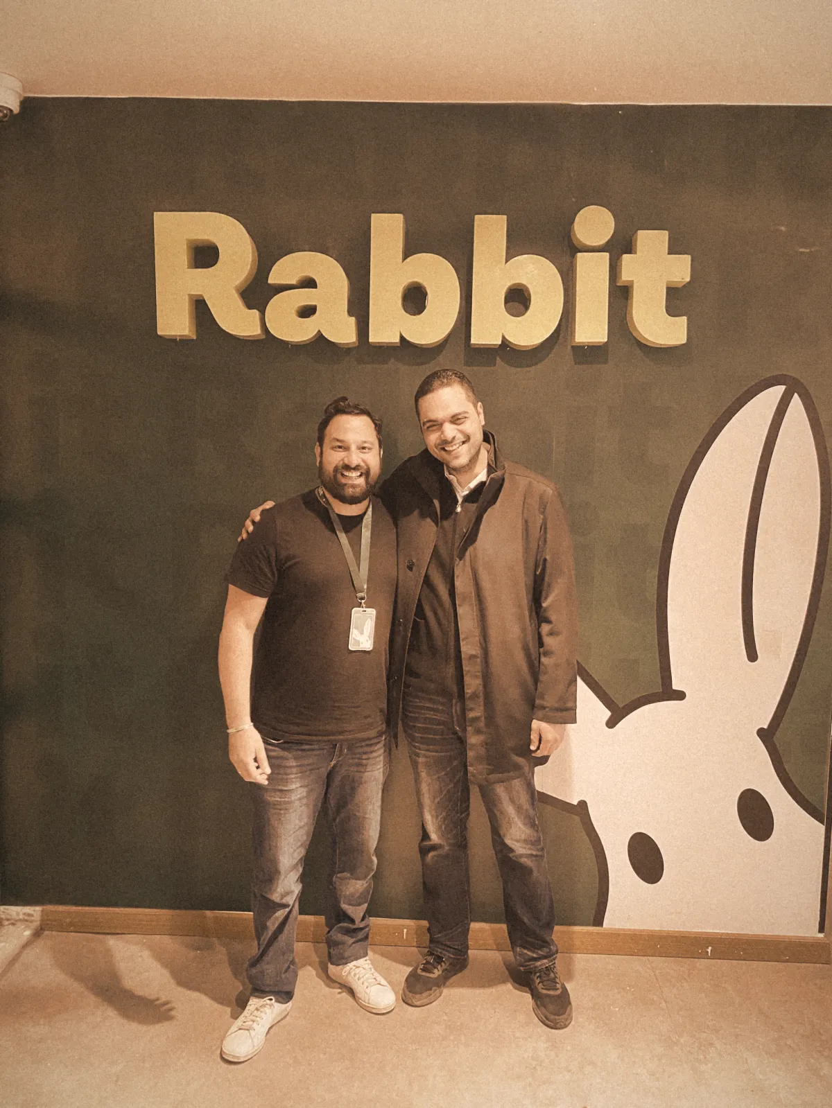 Ahmad at Rabbit headquarters in front of the Rabbit wall